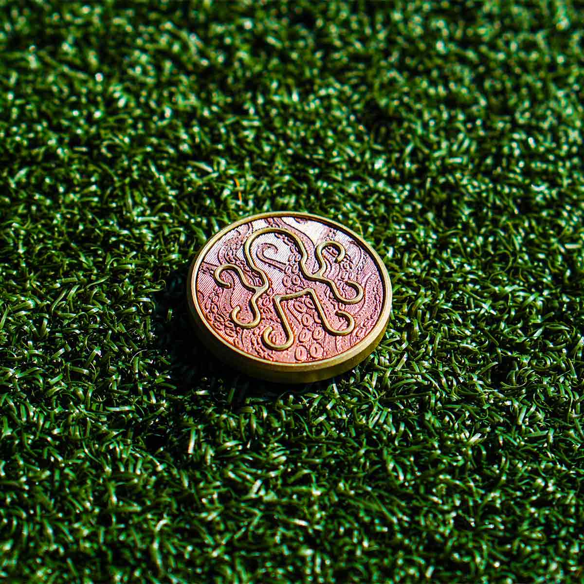 Leviathan golf ball marker front view with copper Kraken tentacle inlay on brass