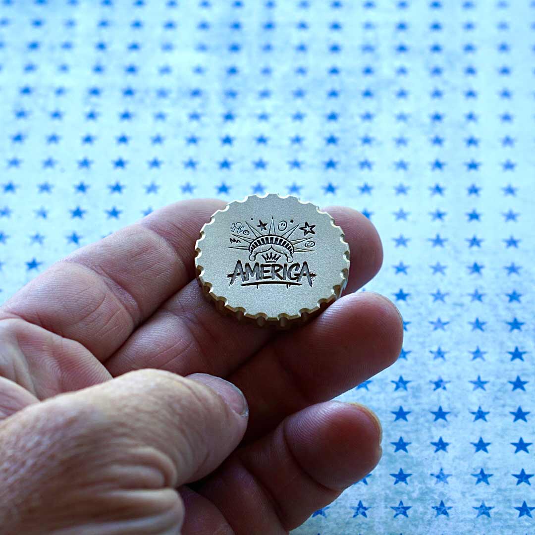 Back of Liberty golf ball marker featuring engraved "America", Liberty crown, smiley face and Kraken logo