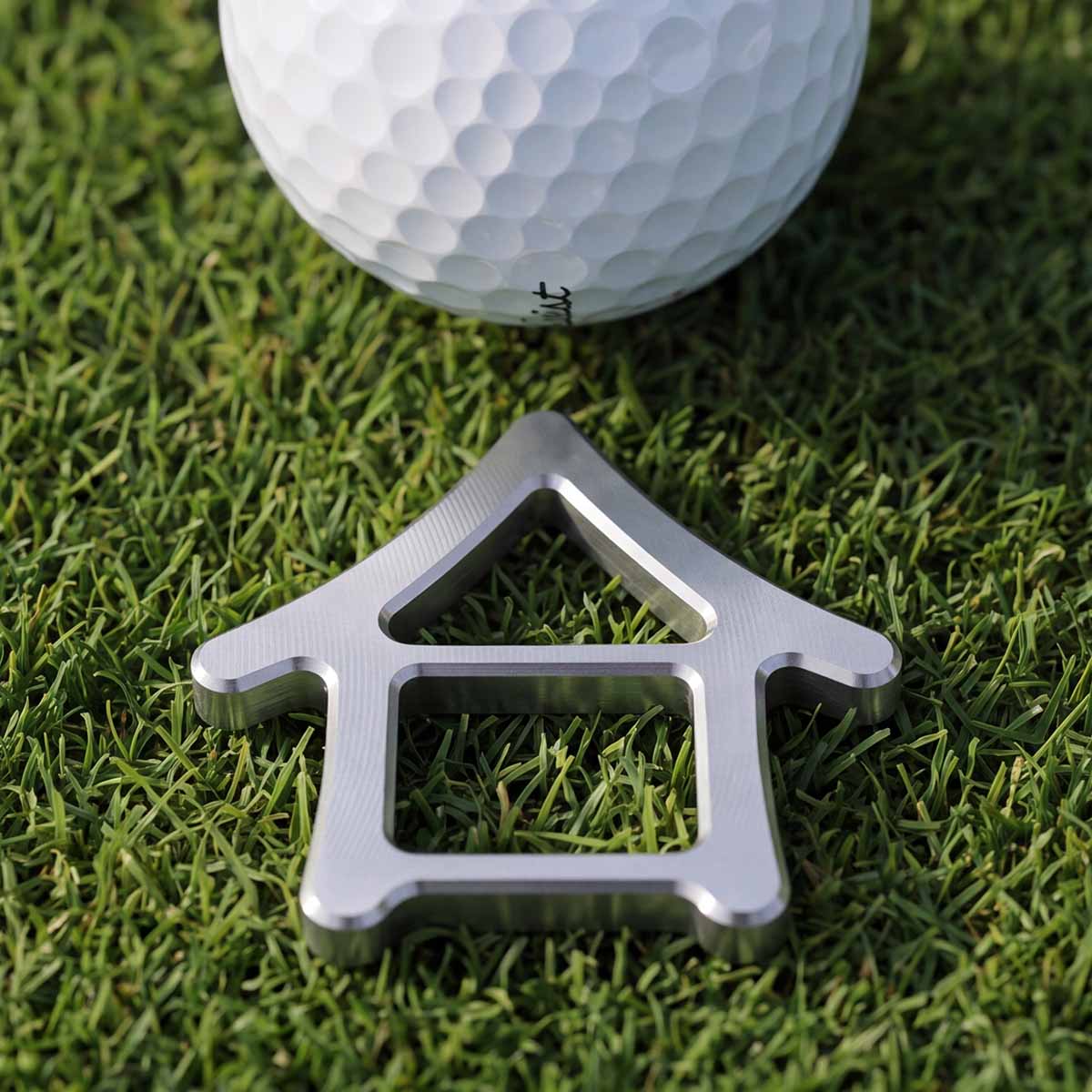 Machiya house-shaped golf ball marker set behind a golf ball on a putting green