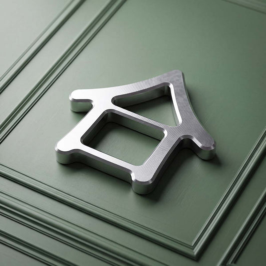 Kraken Golf Machiya stainless steel golf ball marker, house-shaped open frame with visible mill marks, on sage green panel