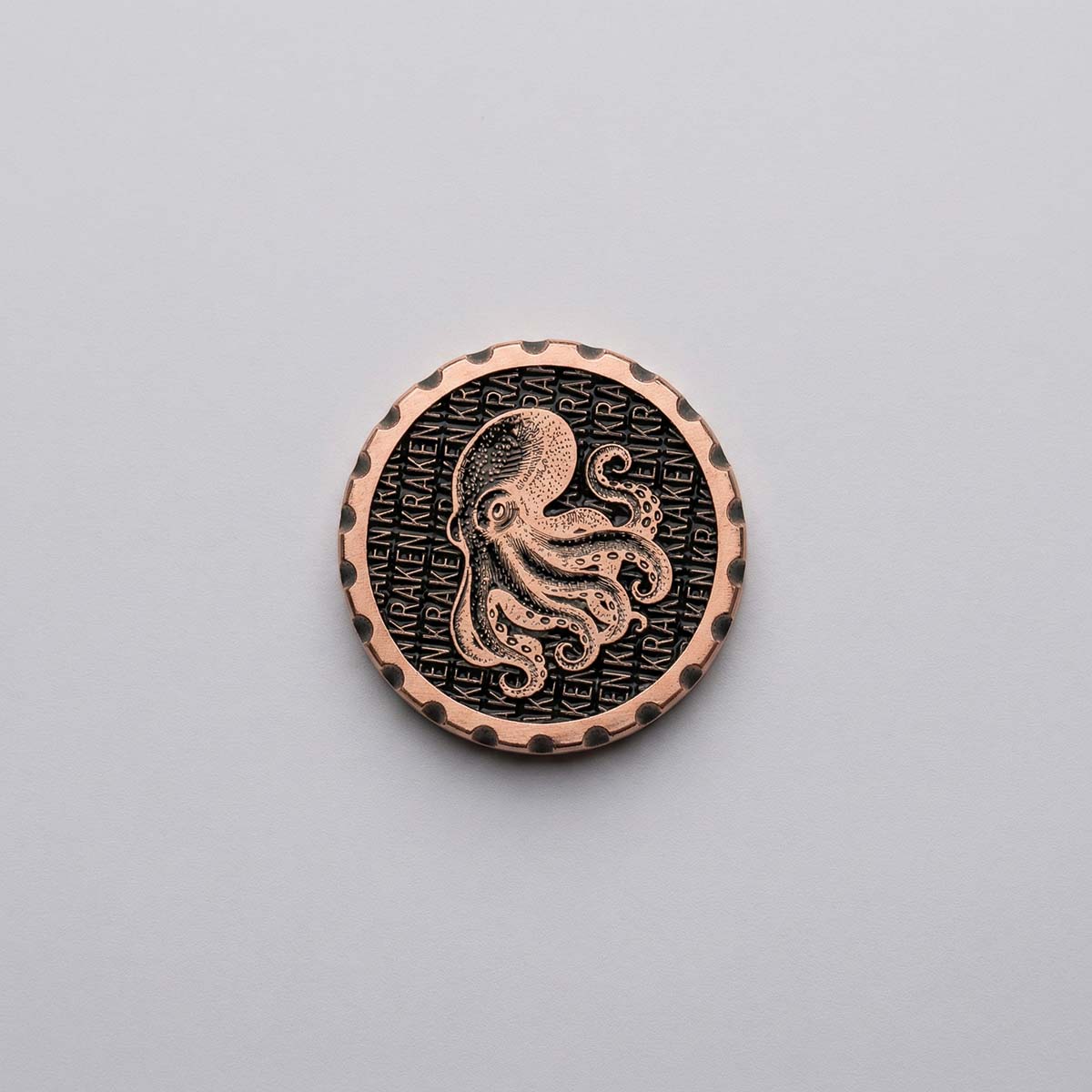 1.35 inch copper golf ball marker with blackened background repeating KRAKEN text