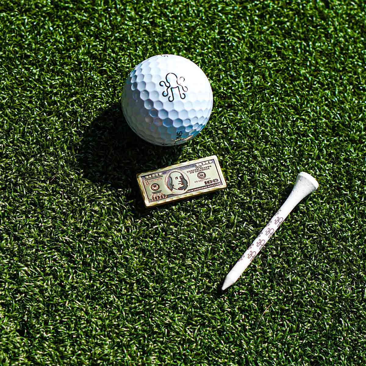 Front of handcrafted Kraken Golf $100 marker in darkened brass with subtle texture