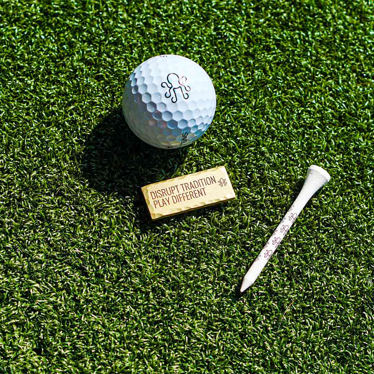 Satin brass backside of $100 bill marker engraved with DISRUPT TRADITION PLAY DIFFERENT