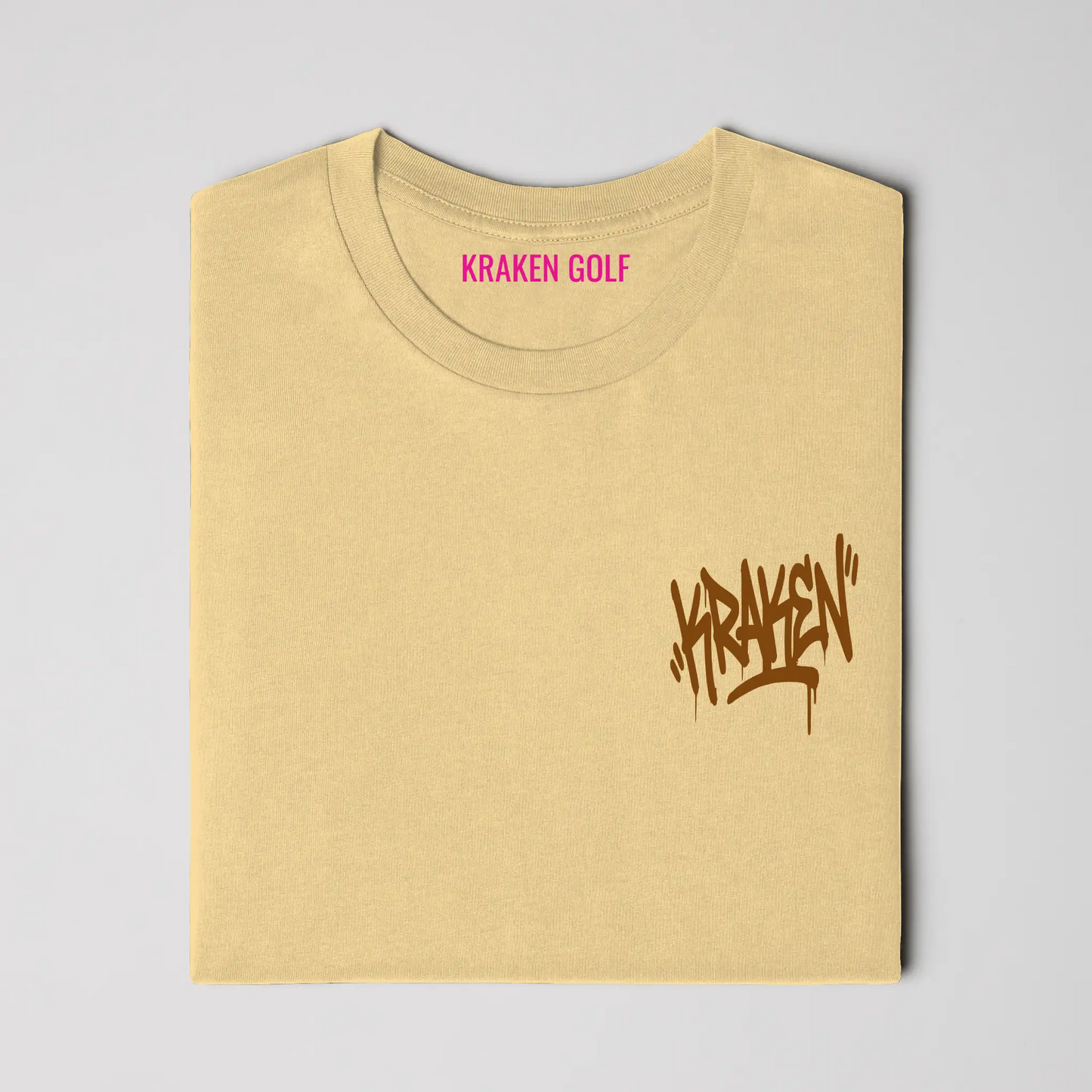 Left chest detail of the butter Origin tee showing the brown Kraken graffiti tag on heavyweight garment-dyed cotton