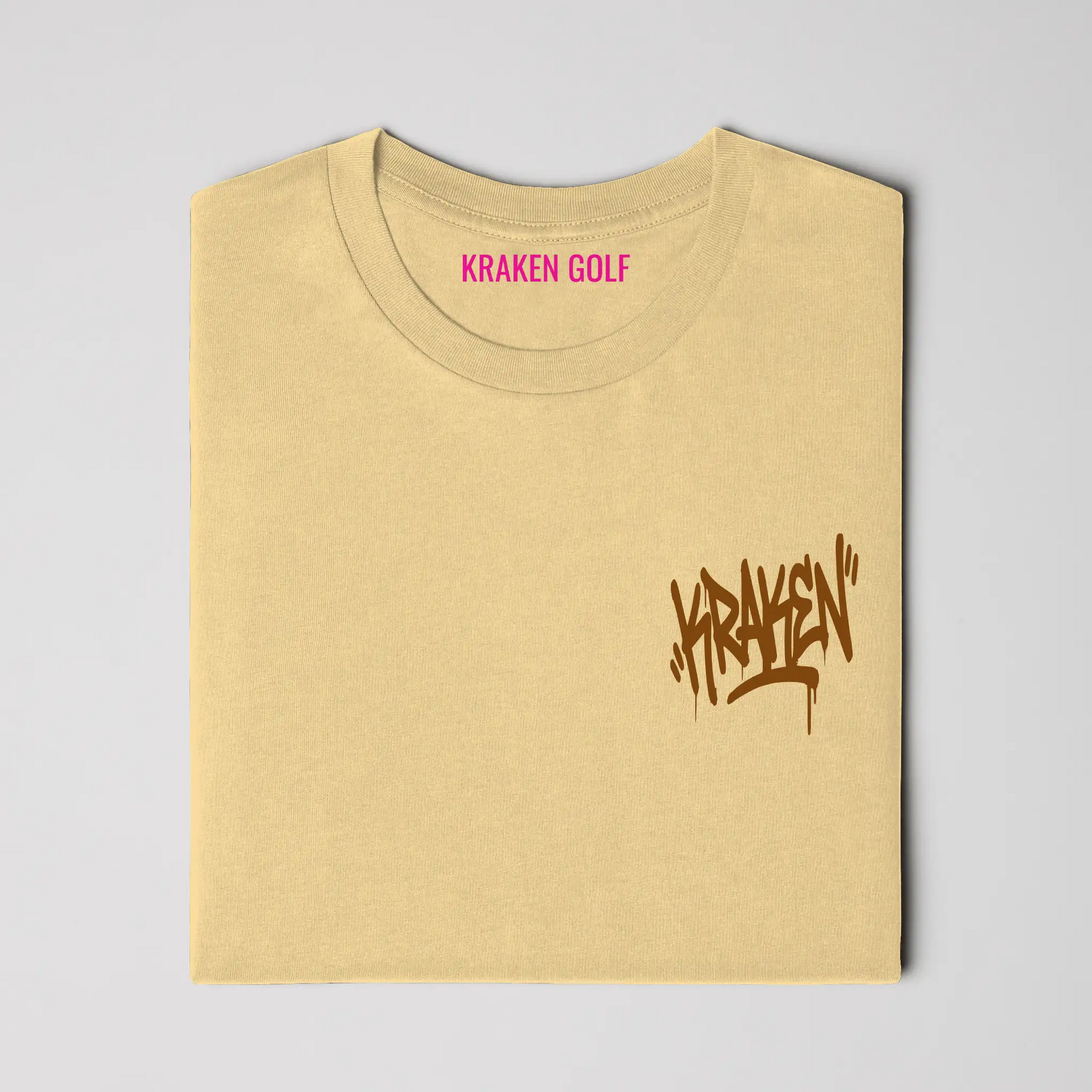 Left chest detail of the butter Origin tee showing the brown Kraken graffiti tag on heavyweight garment-dyed cotton