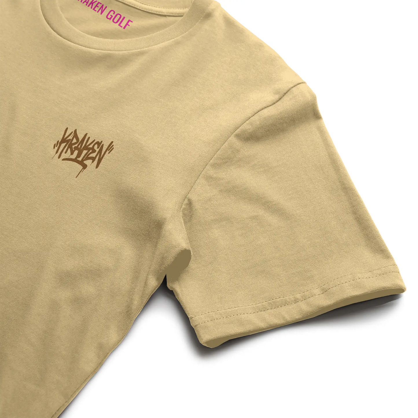 Left chest detail of the butter Origin tee showing the brown Kraken graffiti tag on heavyweight garment-dyed cotton