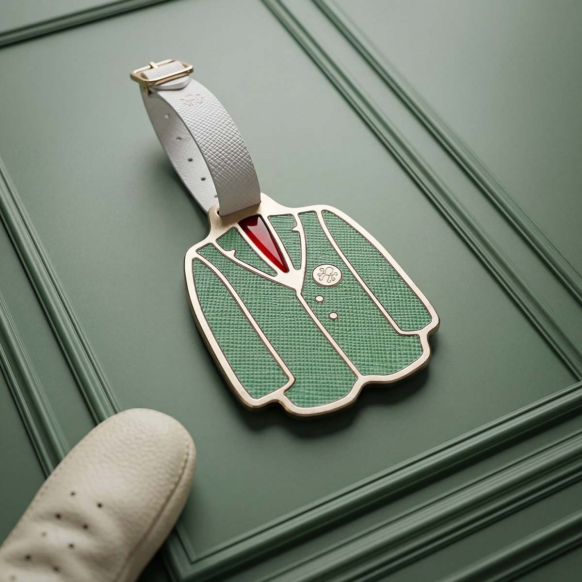 Front of Patron Pass Bag Tag with tailored coat silhouette, green Saffiano leather inlay, and red undershirt paint fill