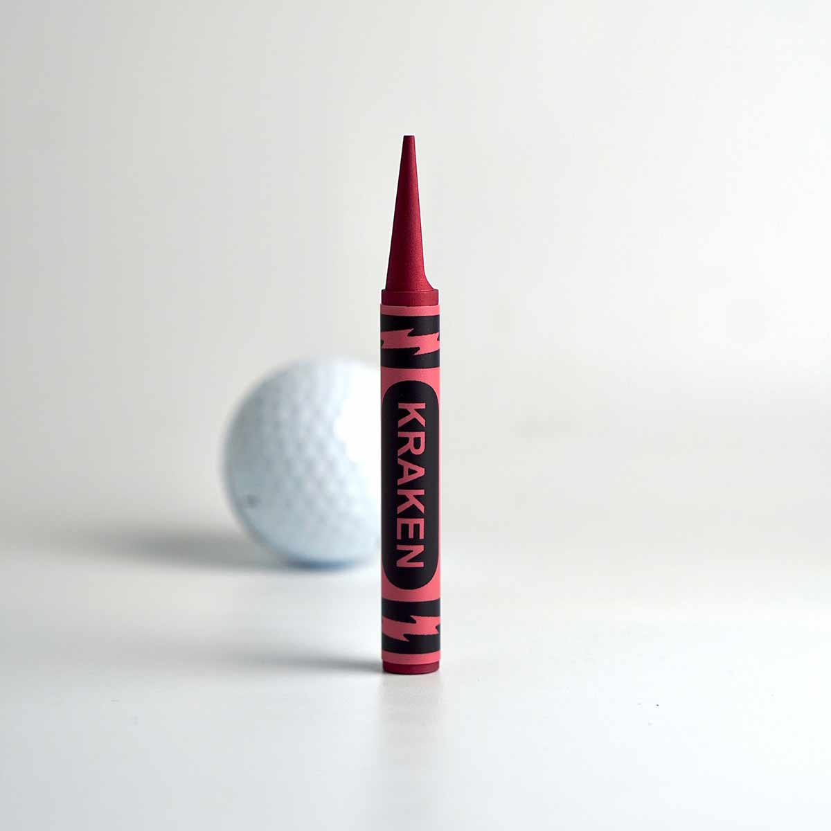 Red Birdie Crayon Divot Tool in red anodized aluminum, shown on putting green