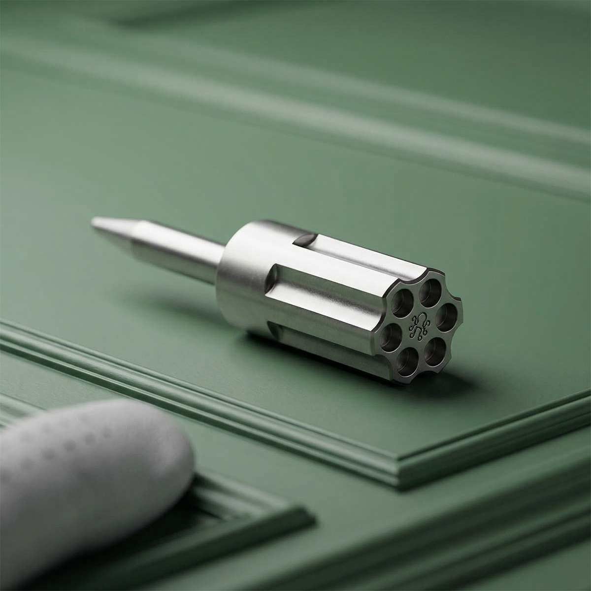 Kraken Revolver Pitch Tool in stainless steel on green background.