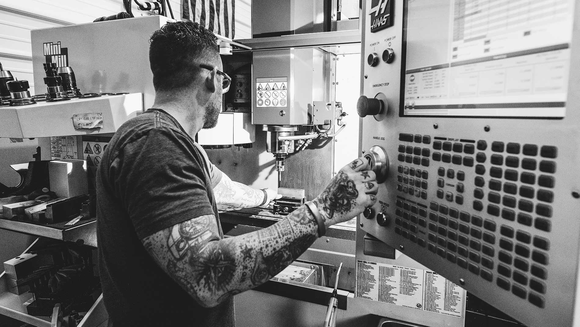 Person operating a machine with control panel in a workshop setting