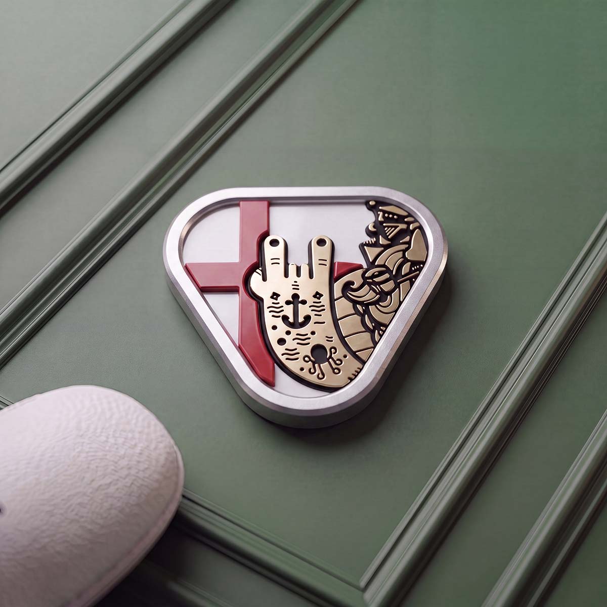 Triangular stainless steel golf ball marker with a polished brass Captain figure throwing horns over the red cross of England on a white inlay.
