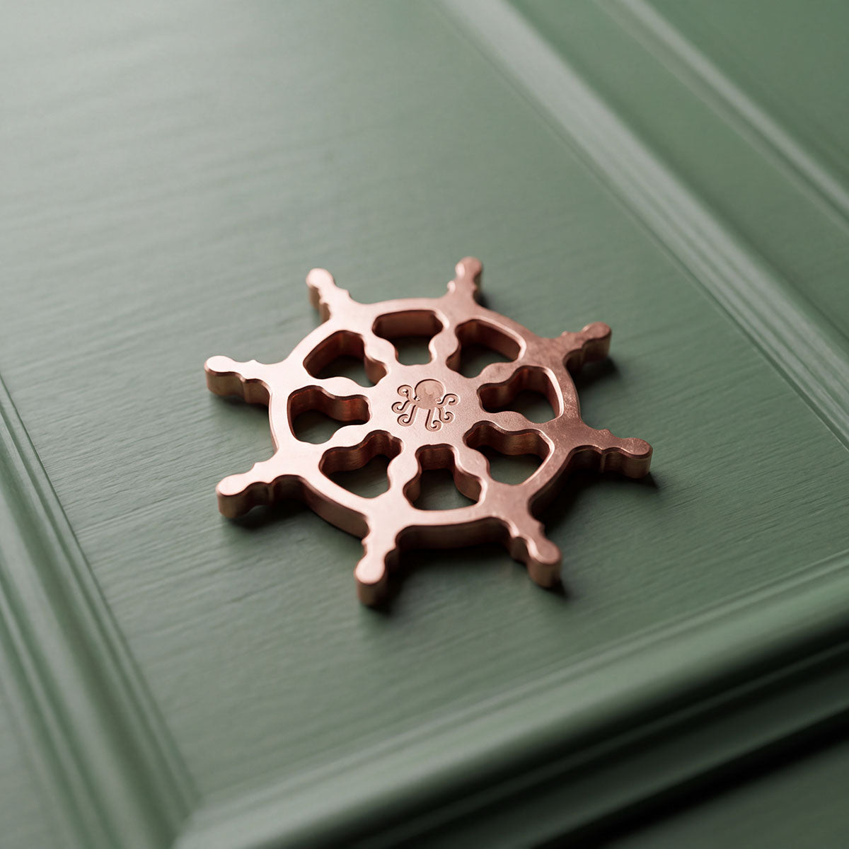 Reverse of The Helm copper golf ball marker showing the laser-engraved Kraken logo at the center