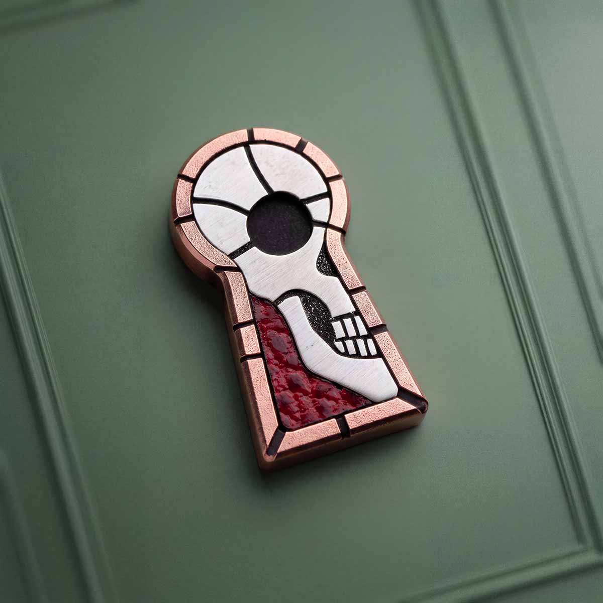 Angled view of The Keep hand-milled copper golf ball marker showing brick-pattern border and skull inlay