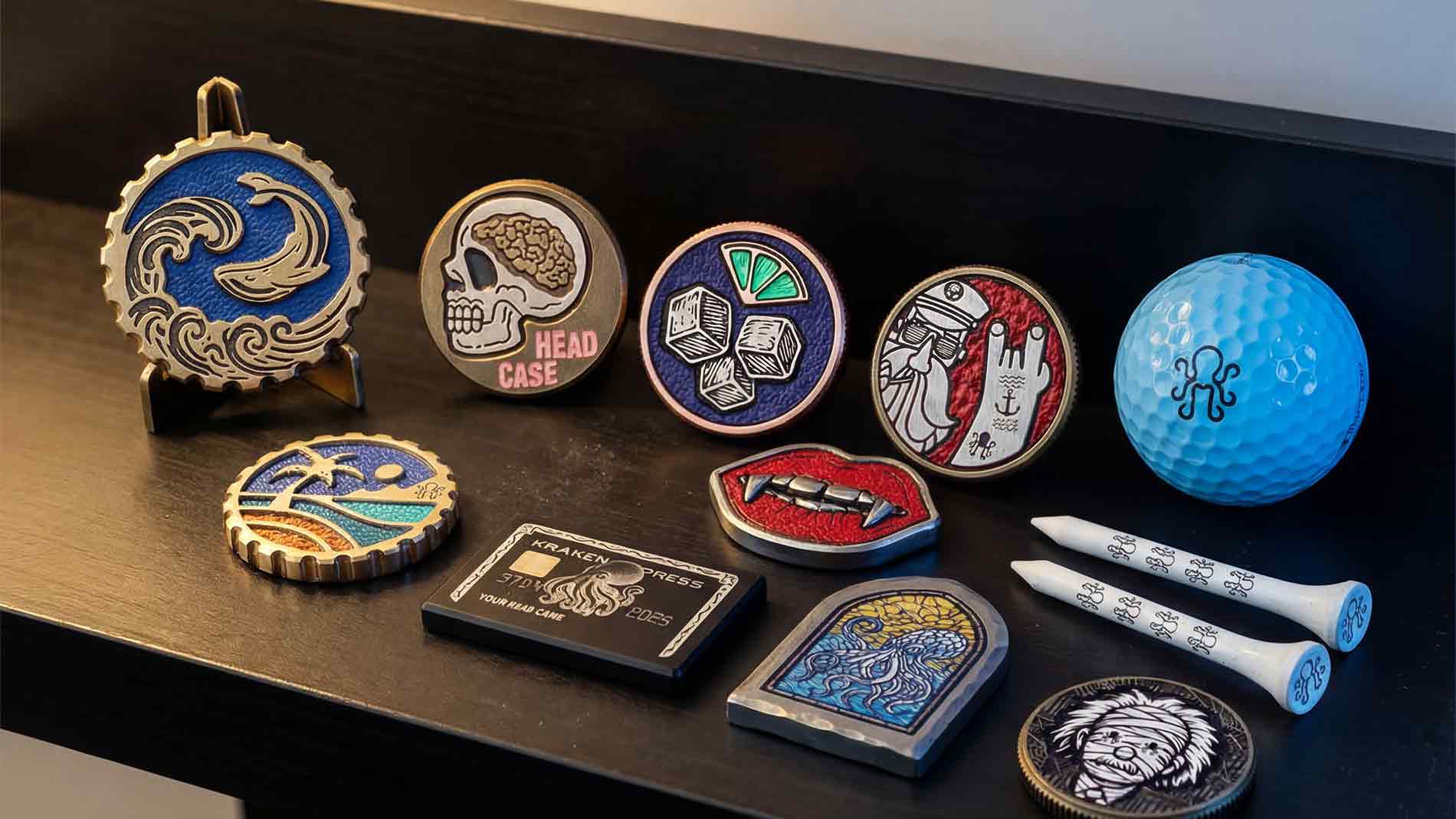 Collection of Kraken Golf ball markers  and a golf ball on a dark surface