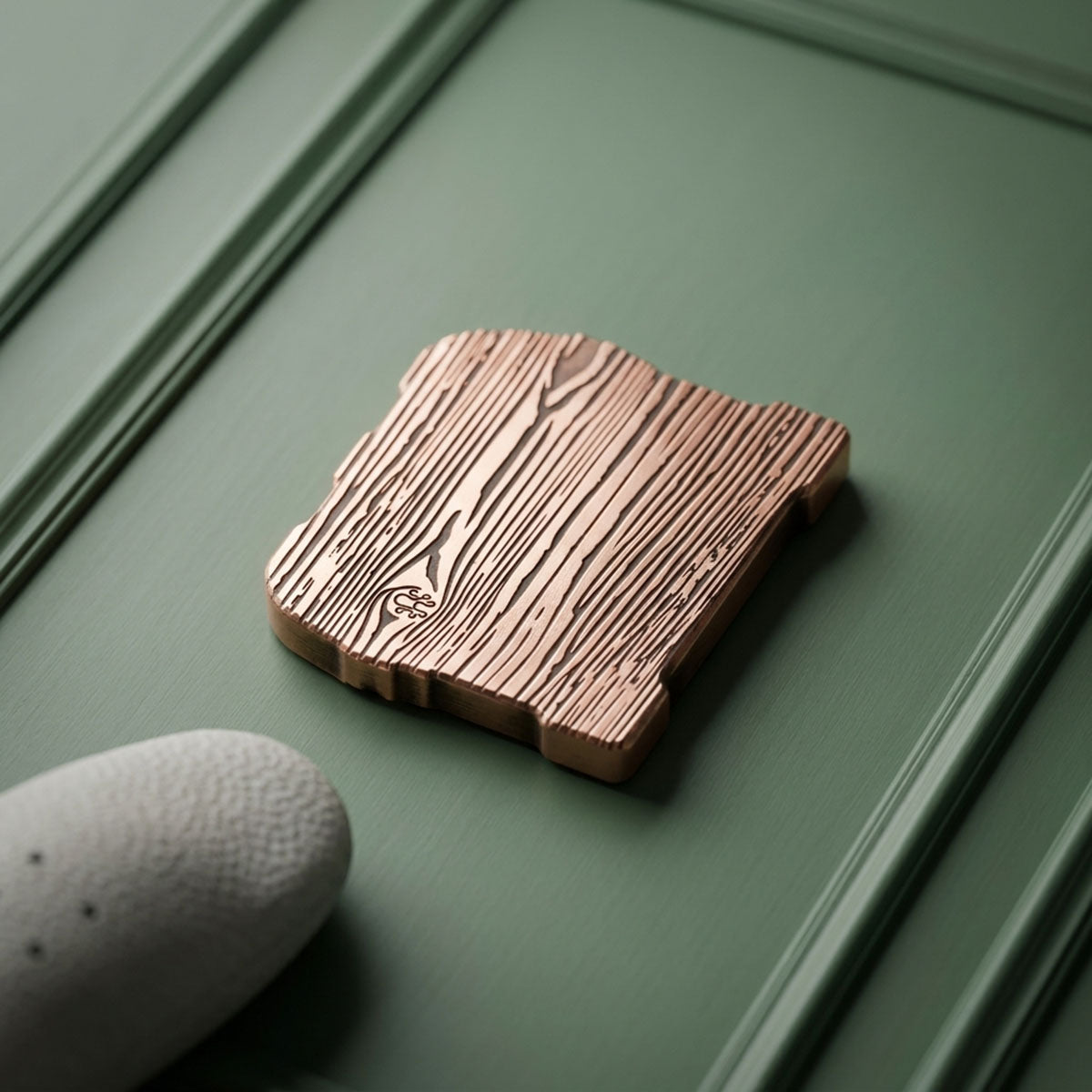 Reverse of copper treasure chest ball marker showing laser-engraved wood grain with hidden Kraken logo