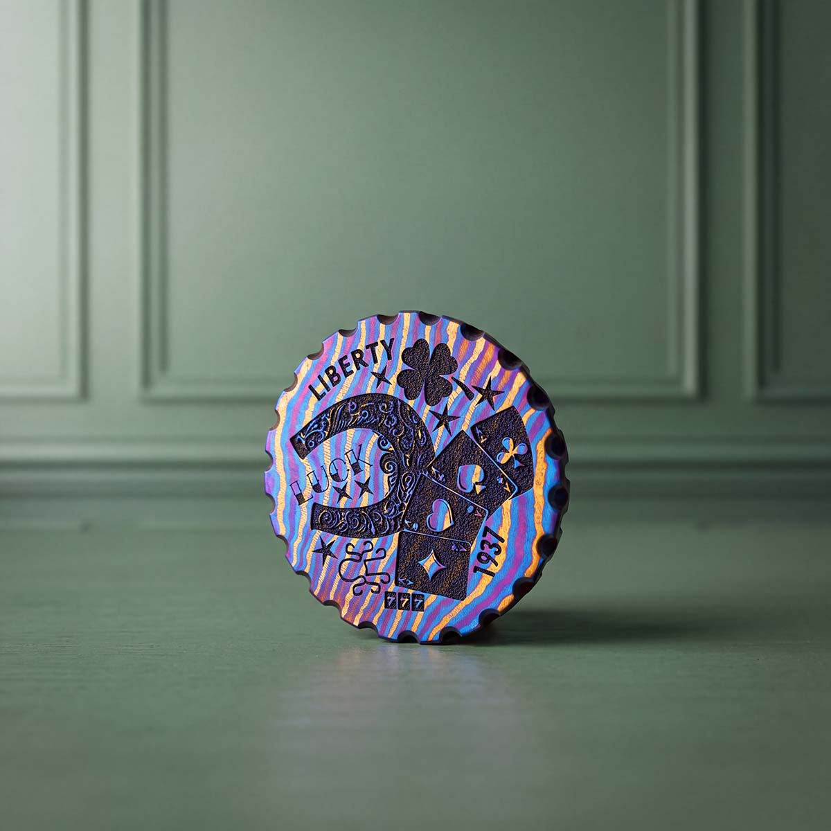 Hobo Luck Timascus golf ball marker front view showing horseshoe, four-leaf clover, playing cards, LIBERTY and LUCK engraving on purple, blue and gold layered titanium