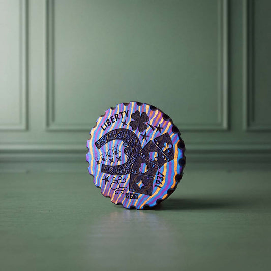Hobo Luck Timascus golf ball marker front view showing horseshoe, four-leaf clover, playing cards, LIBERTY and LUCK engraving on purple, blue and gold layered titanium