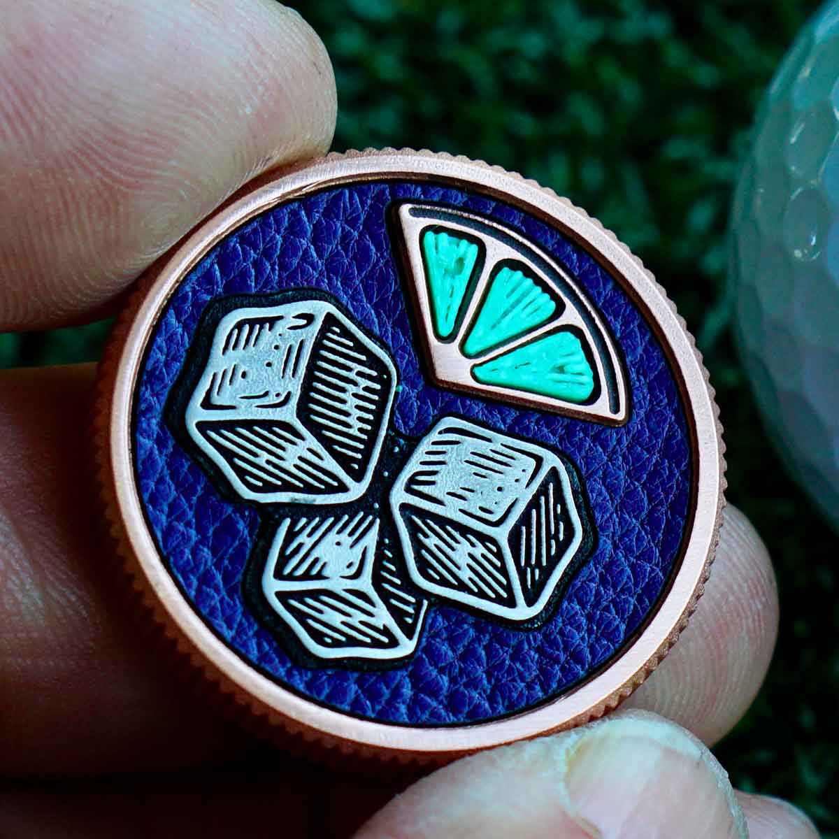 Top-down view of copper golf ball marker with stainless steel ice cubes, 3D printed green lime, and purple Buttero leather inlay