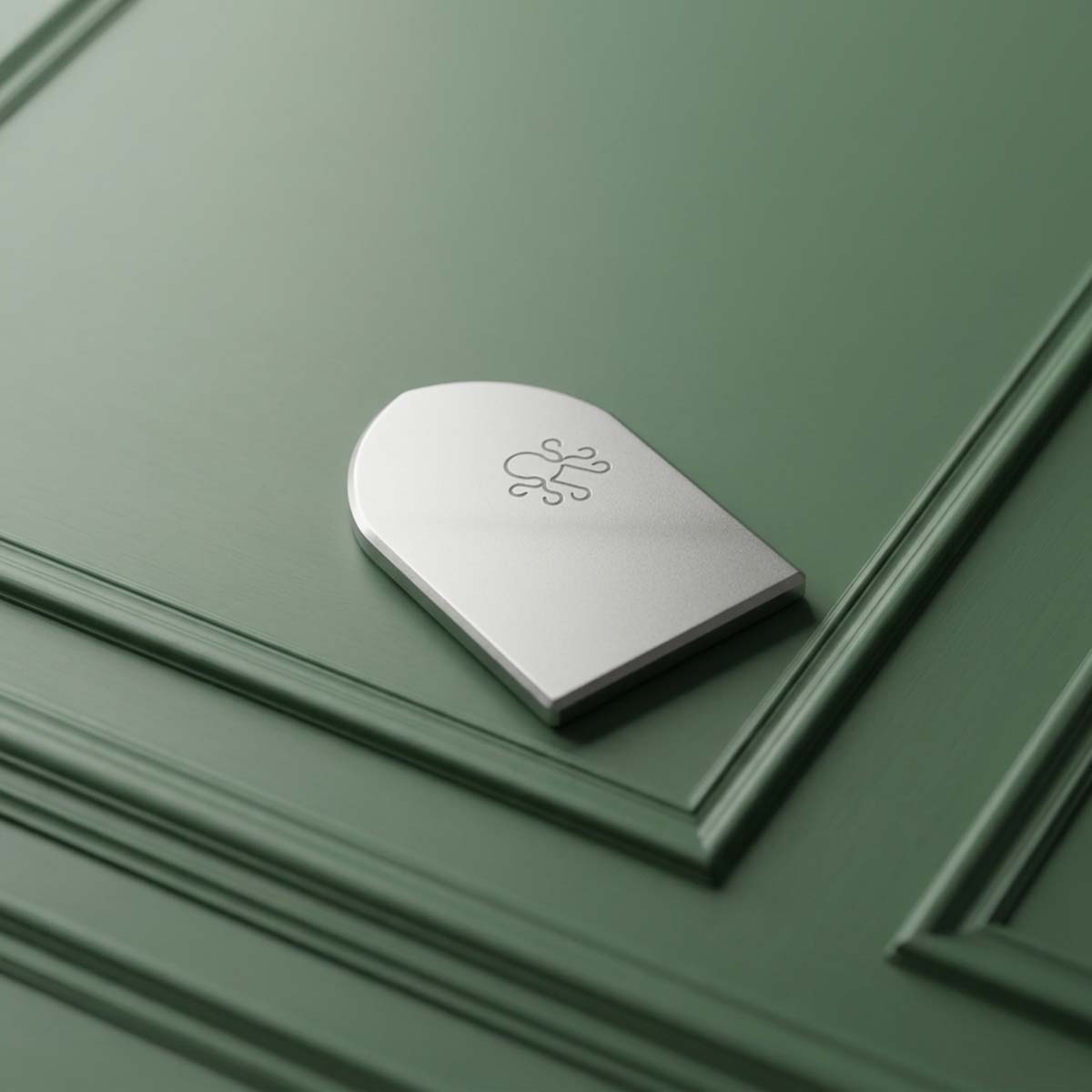The Vesper titanium golf ball marker, back side with laser-annealed Kraken logo, on green paneled wall