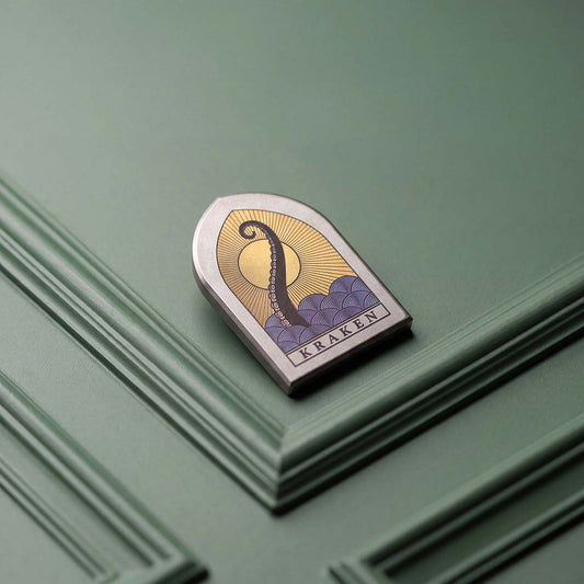 The Vesper gothic window golf ball marker with laser-annealed Kraken tentacle and sunset scene in Grade 2 titanium