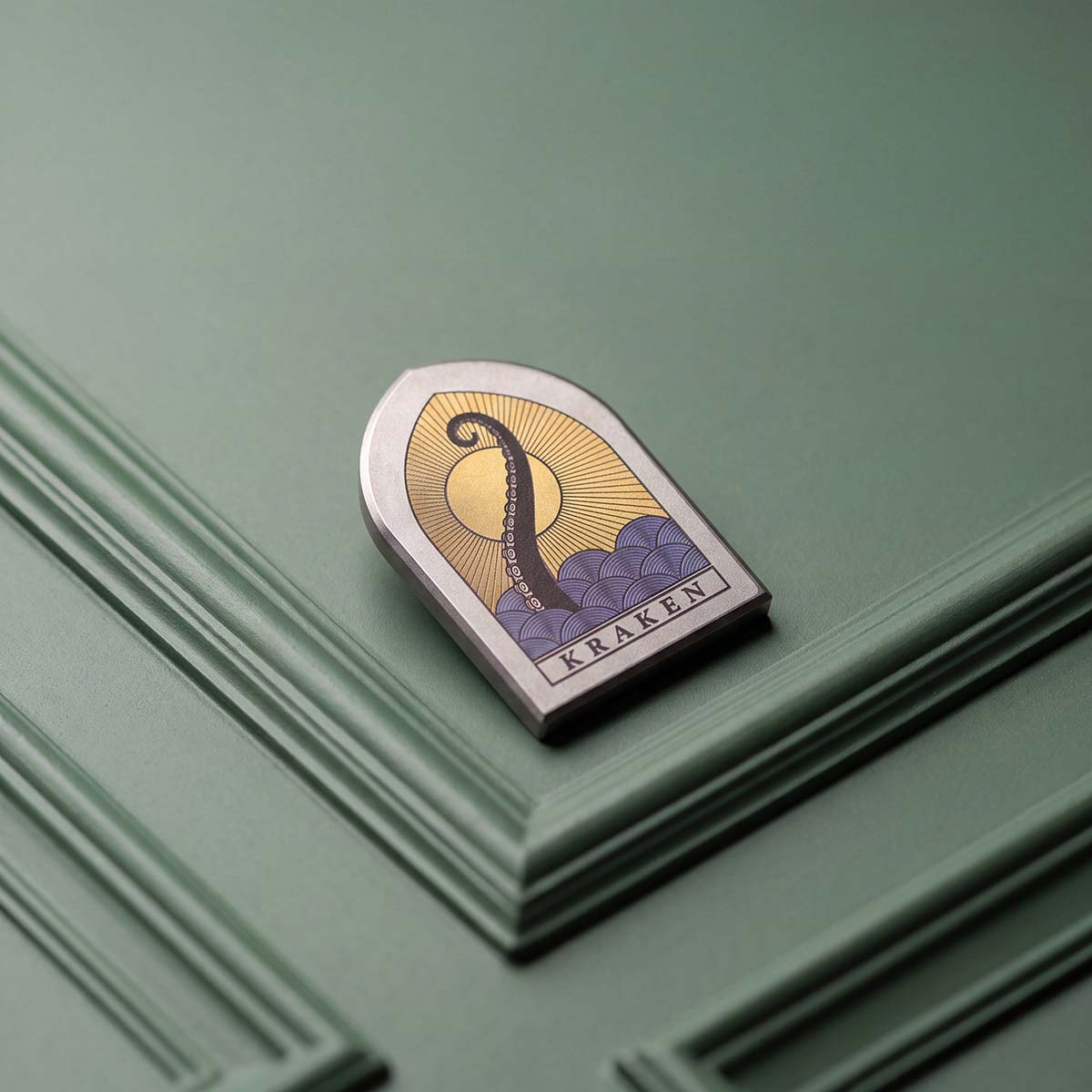 The Vesper gothic window golf ball marker with laser-annealed Kraken tentacle and sunset scene in Grade 2 titanium