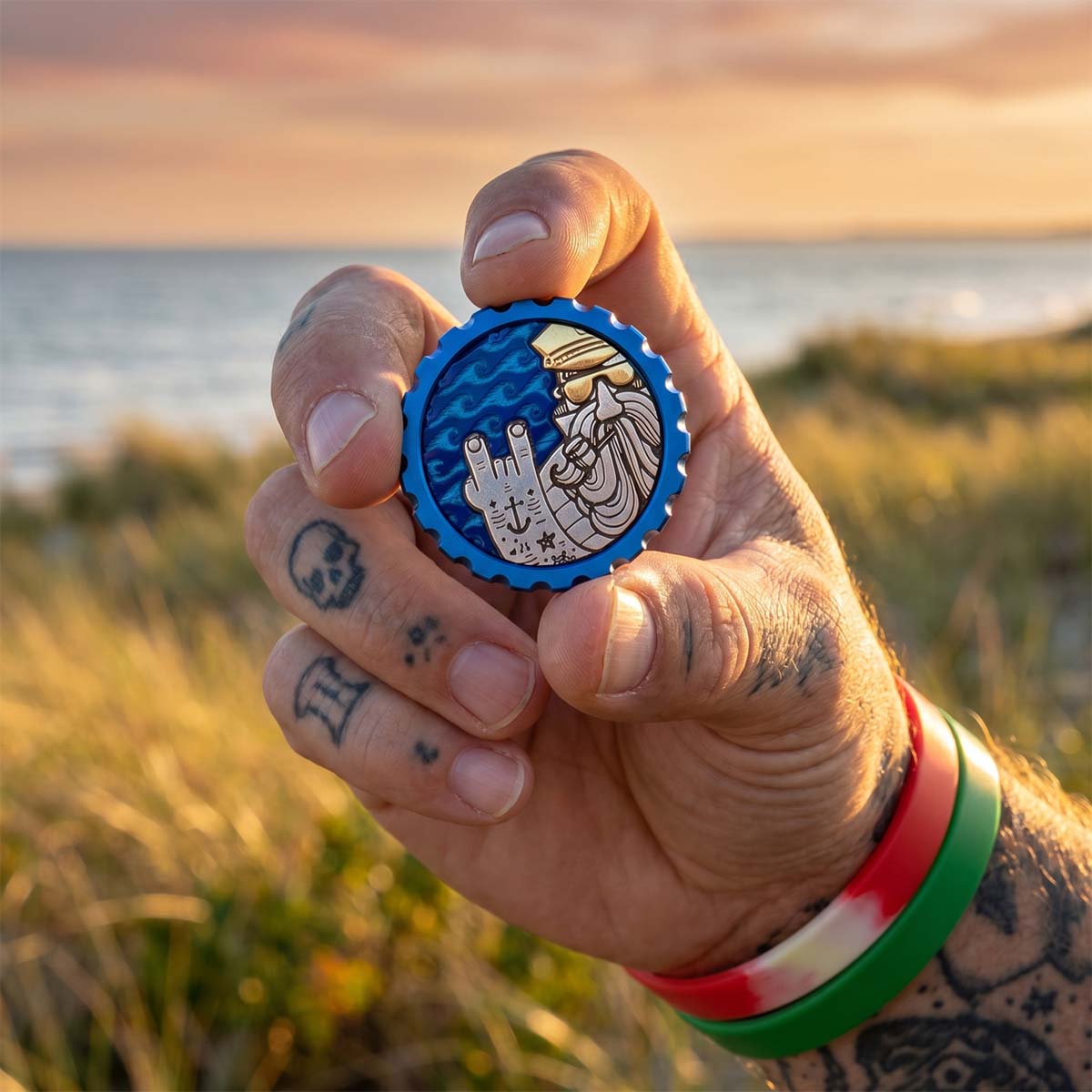 Kraken Golf Watcher ball marker, Southampton 2026 — stainless steel tattooed Captain in a brass cap and sunglasses over a blue ocean-wave inlay.